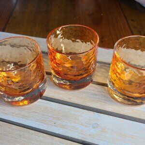 Three dimpled orange whisky glasses.